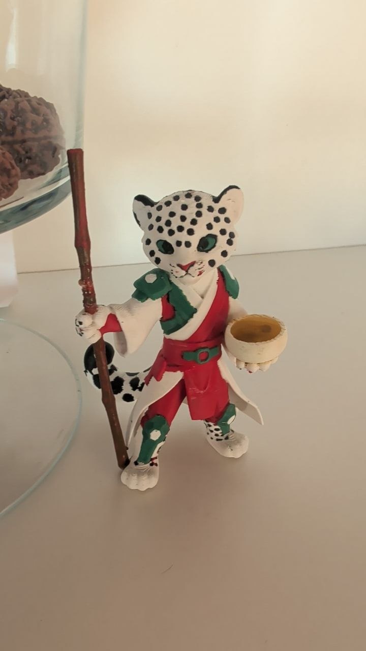 A 3D printing of LeoChi the snow leopard spirit guardian holding his protective staff and singing bowl