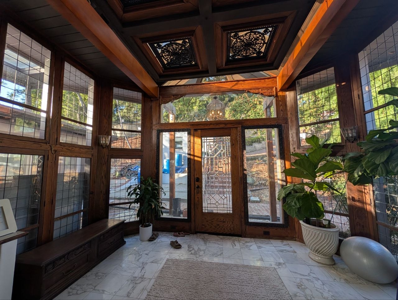 Solarium foyer at OmOrenda.space with coffered timber ceilings, marble tiles, and leaded glass grid walls